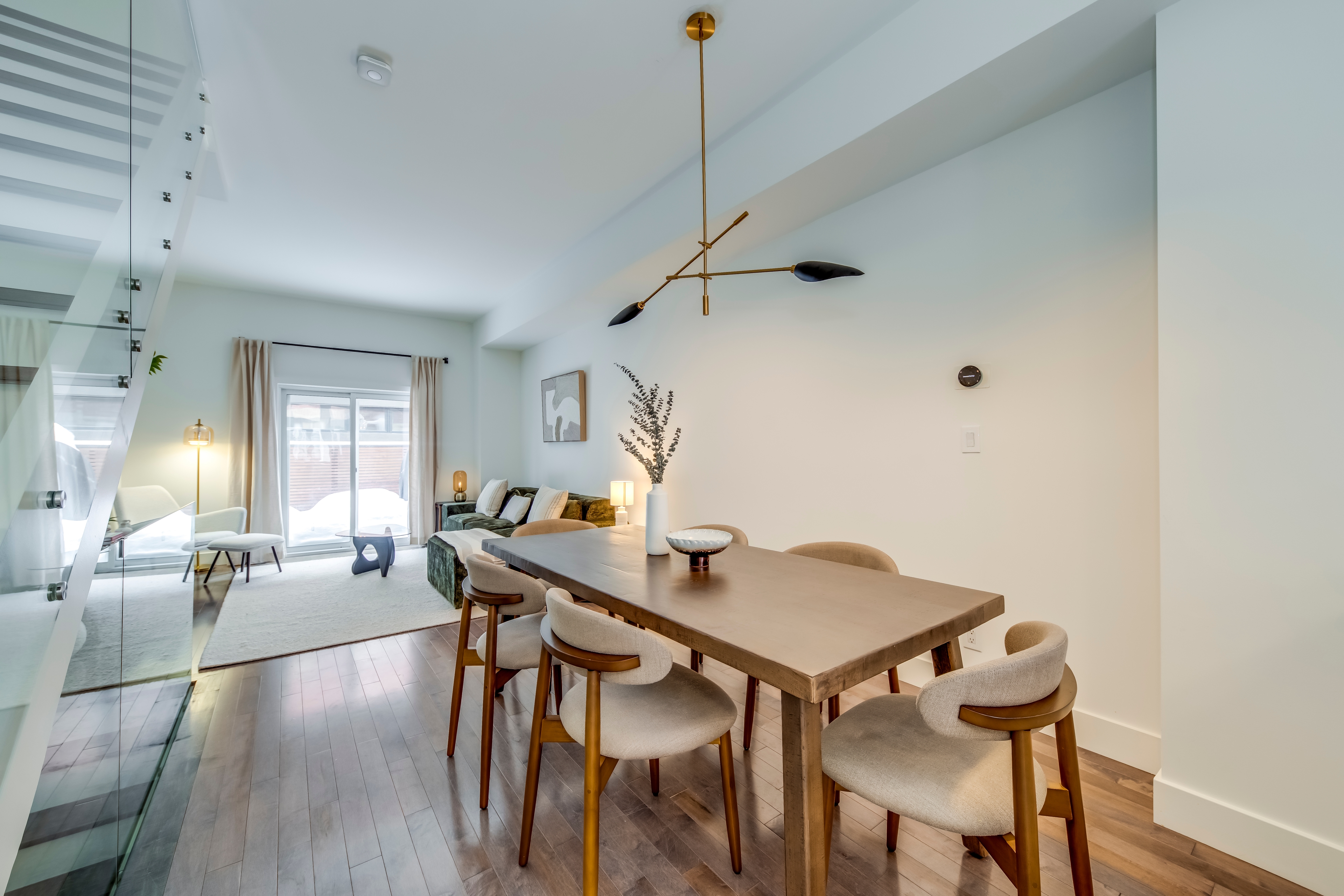 Open-concept dining and living space with hardwood floors, sculptural chandelier, and patio doors in an HSG-managed Toronto rental